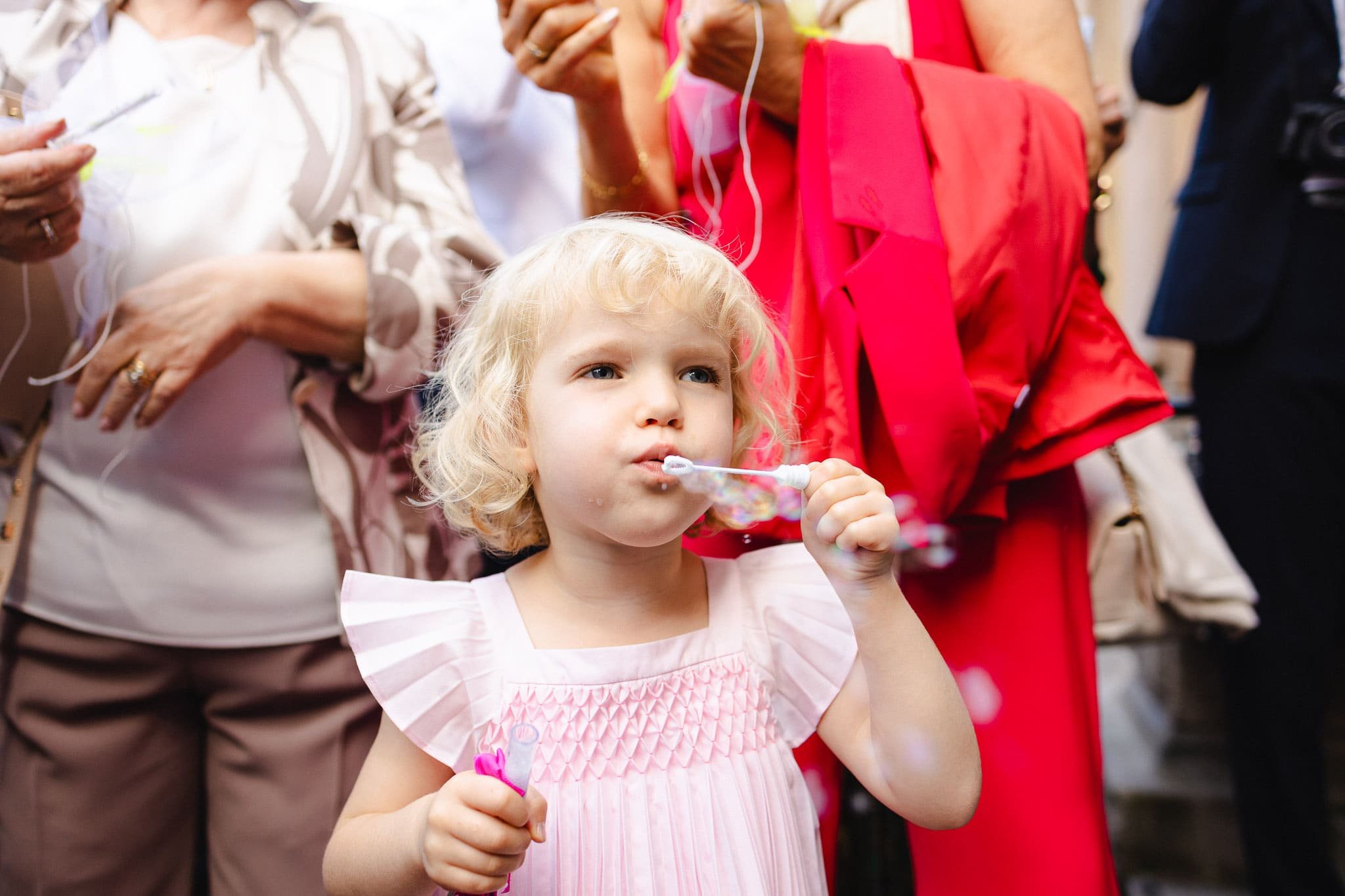Une petite fille souffle des bulles de savon lors de la sortie d'église du mariage de Margaux et Alexis.